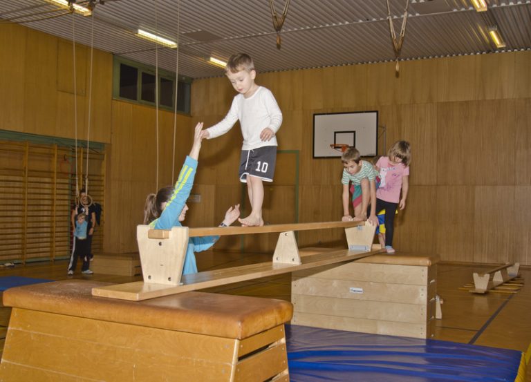 Kinder turnen an Großgeräten in der Turnhalle