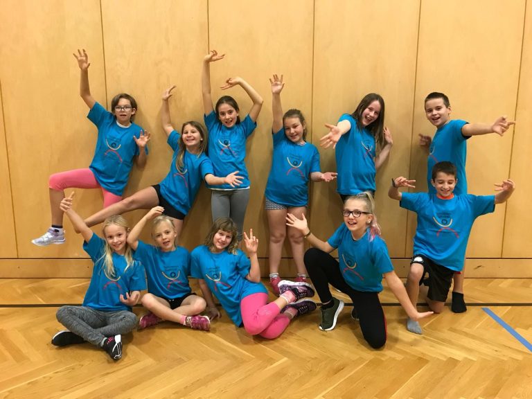 Kinder tanzen gemeinsam zu Musik in der Turnhalle