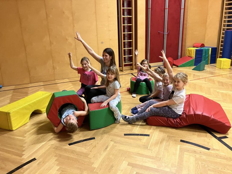 Kinder posieren auf bunten Schaumstoffbausteinen in der Turnhalle