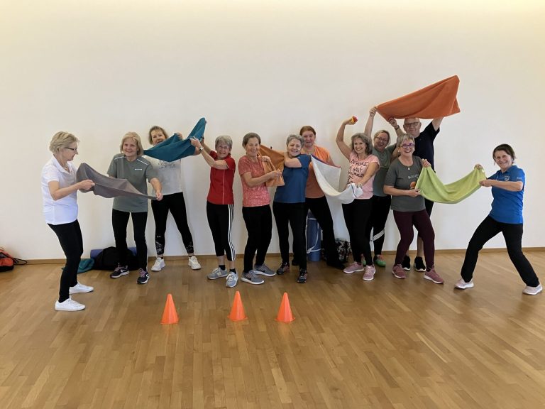 Erwachsenengruppe mit Übungsbändern jubelt in die Kamera