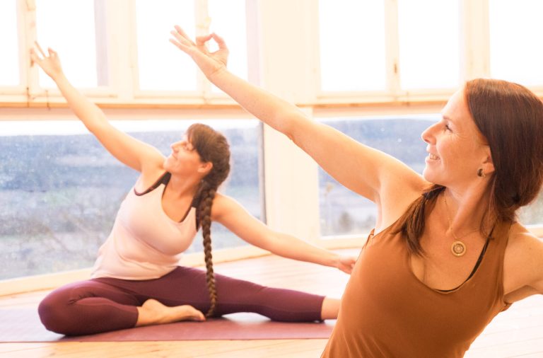 Zwei Frauen üben Yoga-Haltungen in einem hellen Raum
